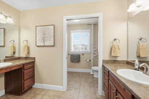 Full bathroom featuring two vanities and light tile patterned floors