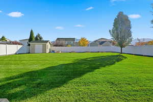 Fenced backyard featuring a storage shed