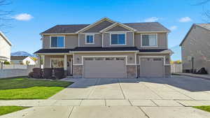 Craftsman-style home featuring a garage, driveway, stone siding, and a mountain view