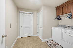 Laundry room featuring light tile patterned flooring, washing machine and dryer, and cabinet space