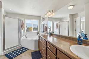Bathroom with a shower stall, double vanity, a garden tub, light tile patterned flooring, and a textured ceiling