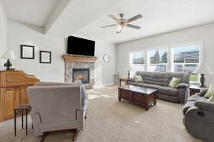 Living room with light carpet, a fireplace, and a ceiling fan