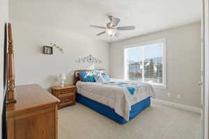 Bedroom featuring light colored carpet, ceiling fan, and a textured ceiling
