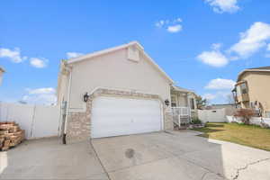 View of side of home with stucco siding, concrete driveway, a gate, and a garage