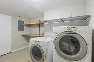 Laundry area with electric panel, separate washer and dryer, and a textured ceiling