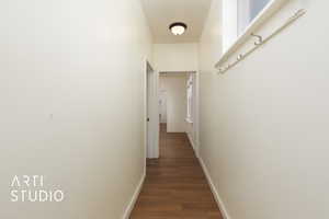 Hallway featuring dark wood-style floors and baseboards