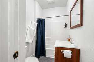 Bathroom with vanity, a textured wall, and shower / bath combination with curtain