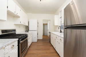 Kitchen with appliances with stainless steel finishes, light countertops, white cabinetry, and dark wood finished floors