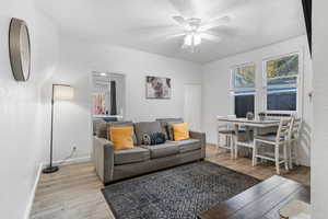 Living area featuring light wood finished floors, plenty of natural light, and a ceiling fan