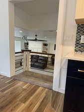 Bar featuring wood finished floors, light stone counters, backsplash, dark cabinetry, and a textured ceiling