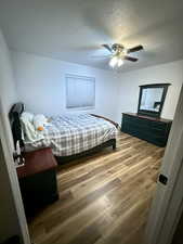 Bedroom featuring light wood finished floors, a textured ceiling, and ceiling fan