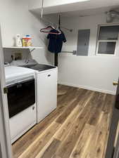 Laundry area featuring electric panel, light wood-type flooring, and washing machine and dryer
