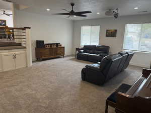 Living room with a ceiling fan, a textured ceiling, light carpet, and recessed lighting