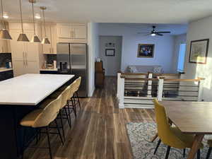 Dining space with a textured ceiling, dark wood-style floors, and a ceiling fan
