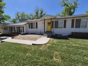 Ranch-style home featuring board and batten siding and a front lawn