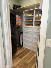 Spacious closet featuring dark wood-style flooring and stacked washer / dryer