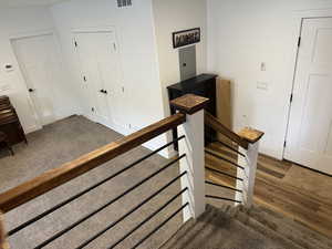 Stairs with electric panel, carpet flooring, and wood finished floors