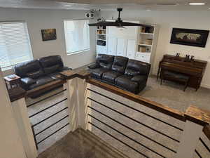Living room featuring dark colored carpet, a textured ceiling, and a ceiling fan