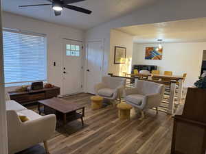 Living area with a textured ceiling, wood finished floors, a ceiling fan, and vaulted ceiling
