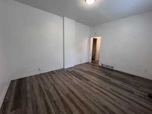 Unfurnished room featuring dark wood-style floors and baseboards
