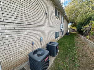 View of side of property with brick siding, a patio, and a yard