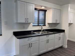 Kitchen with dark countertops, white cabinetry, and dark wood-style floors