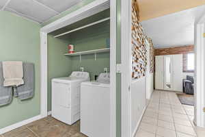 Washroom with light tile patterned flooring and independent washer and dryer
