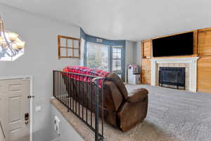 Carpeted living room featuring a fireplace, a textured ceiling, a chandelier, and wood walls