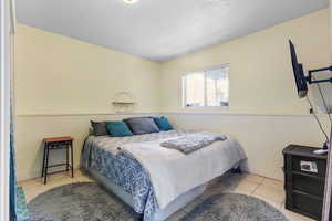 Bedroom with light tile patterned floors and a textured ceiling
