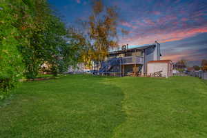 Back of house at dusk with a trampoline, a chimney, a deck, and stairs