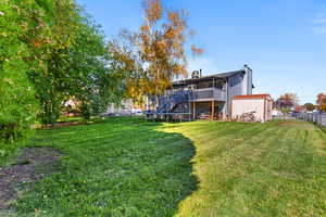 Rear view of property with a trampoline, a chimney, a wooden deck, and stairs