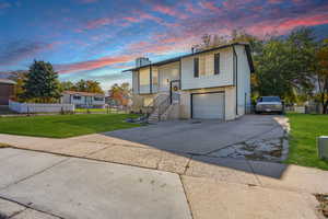 Split foyer home featuring driveway, brick siding, a chimney, and an attached garage