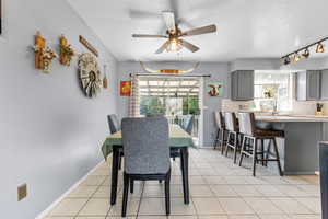 Dining area featuring light tile patterned flooring, a textured ceiling, and a ceiling fan