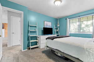 Bedroom with light colored carpet and a textured ceiling