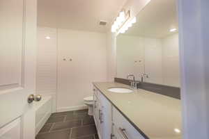 Full bath featuring vanity, dark tile patterned flooring, and shower / washtub combination