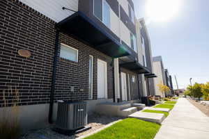 View of property exterior with a central AC unit and brick siding
