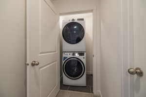 Laundry area featuring stacked washer and clothes dryer and tile patterned flooring