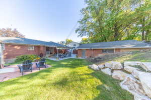 Back of property featuring a patio, brick siding, and roof with shingles