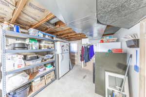 Unfinished below grade area with freestanding refrigerator