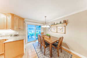 Dining area featuring light wood-style floors, crown molding, and a chandelier