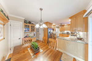 Dining area featuring ceiling fan, crown molding, a chandelier, and light wood finished floors