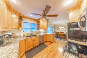 Kitchen with crown molding, open shelves, appliances with stainless steel finishes, tasteful backsplash, and light wood-style flooring