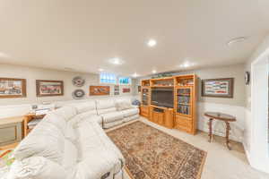 Carpeted living room with a wainscoted wall and recessed lighting