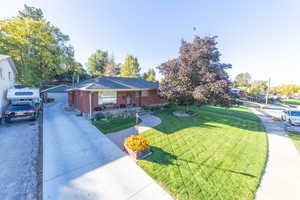 Ranch-style house with a front yard, brick siding, and covered porch