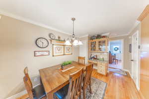 Dining space featuring light wood-style floors, ornamental molding, and a chandelier