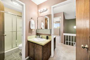 Bathroom featuring a textured wall, vanity, a shower stall, and light carpet