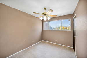 Unfurnished room featuring a textured wall, light carpet, a textured ceiling, and ceiling fan
