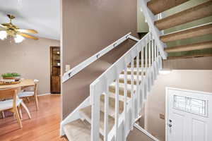 Stairway featuring a textured wall, wood finished floors, a ceiling fan, and lofted ceiling