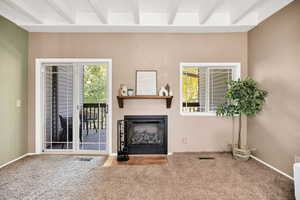 Carpeted living area featuring beamed ceiling, a fireplace, and a textured wall