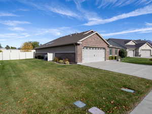 View of side of property with brick siding, concrete driveway, an attached garage, and a residential view